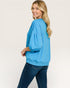 Woman wearing a blue sweatshirt and jeans on a beige background