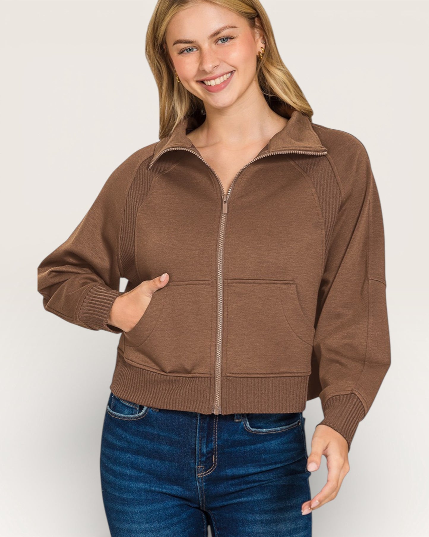 Woman wearing a brown zip-up jacket on a white background