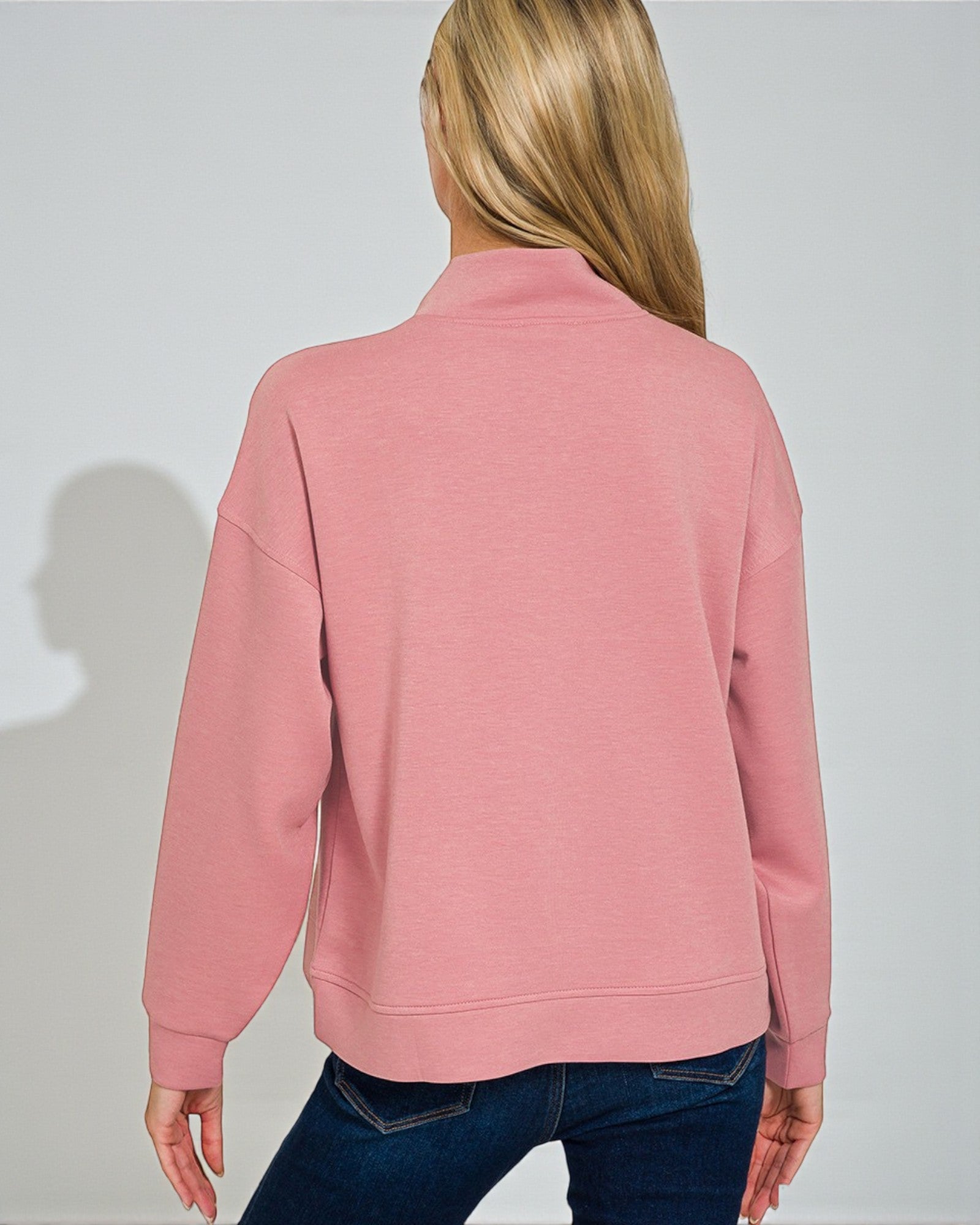Person wearing a pink sweatshirt with a plain background