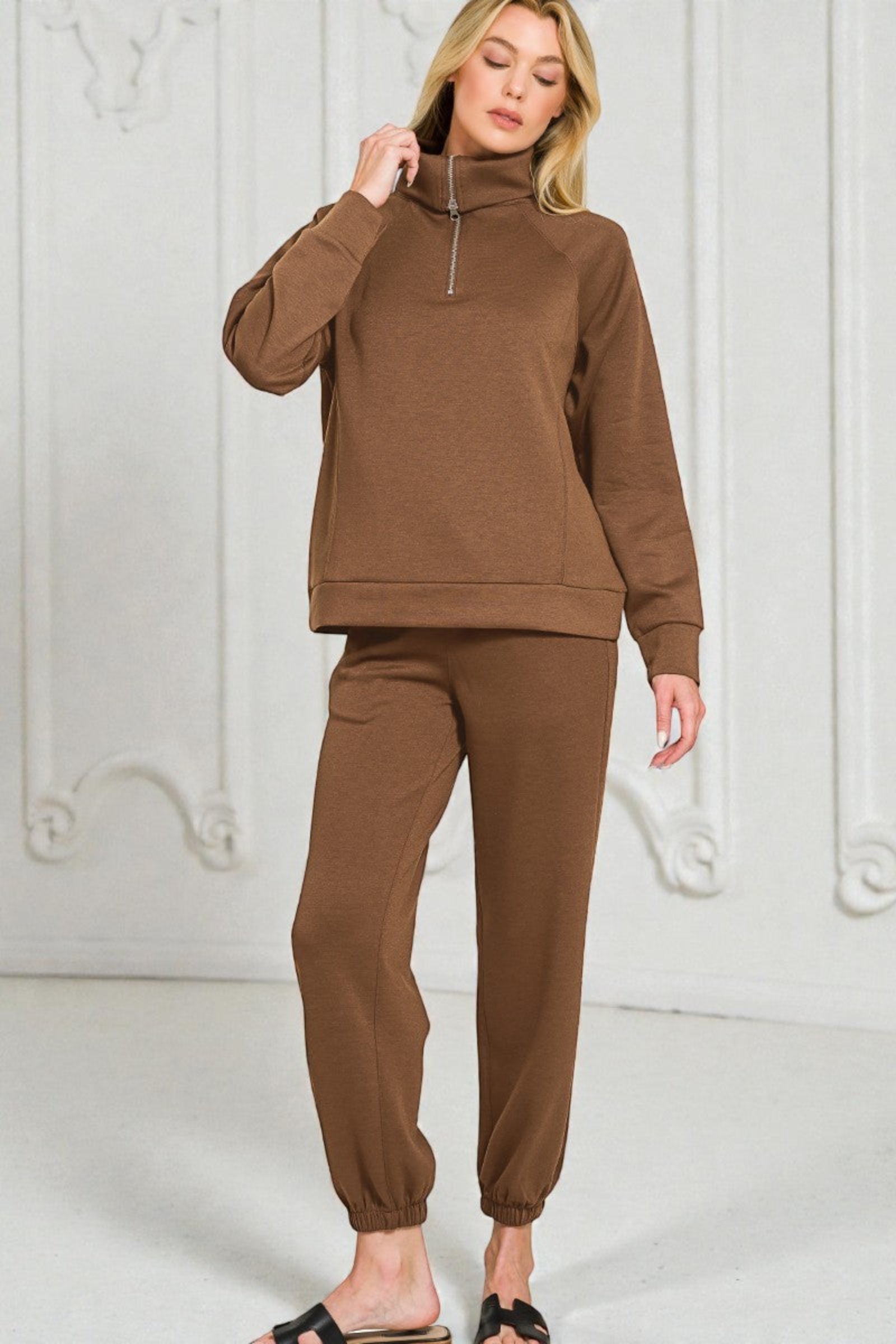 Woman wearing a brown tracksuit against a white background