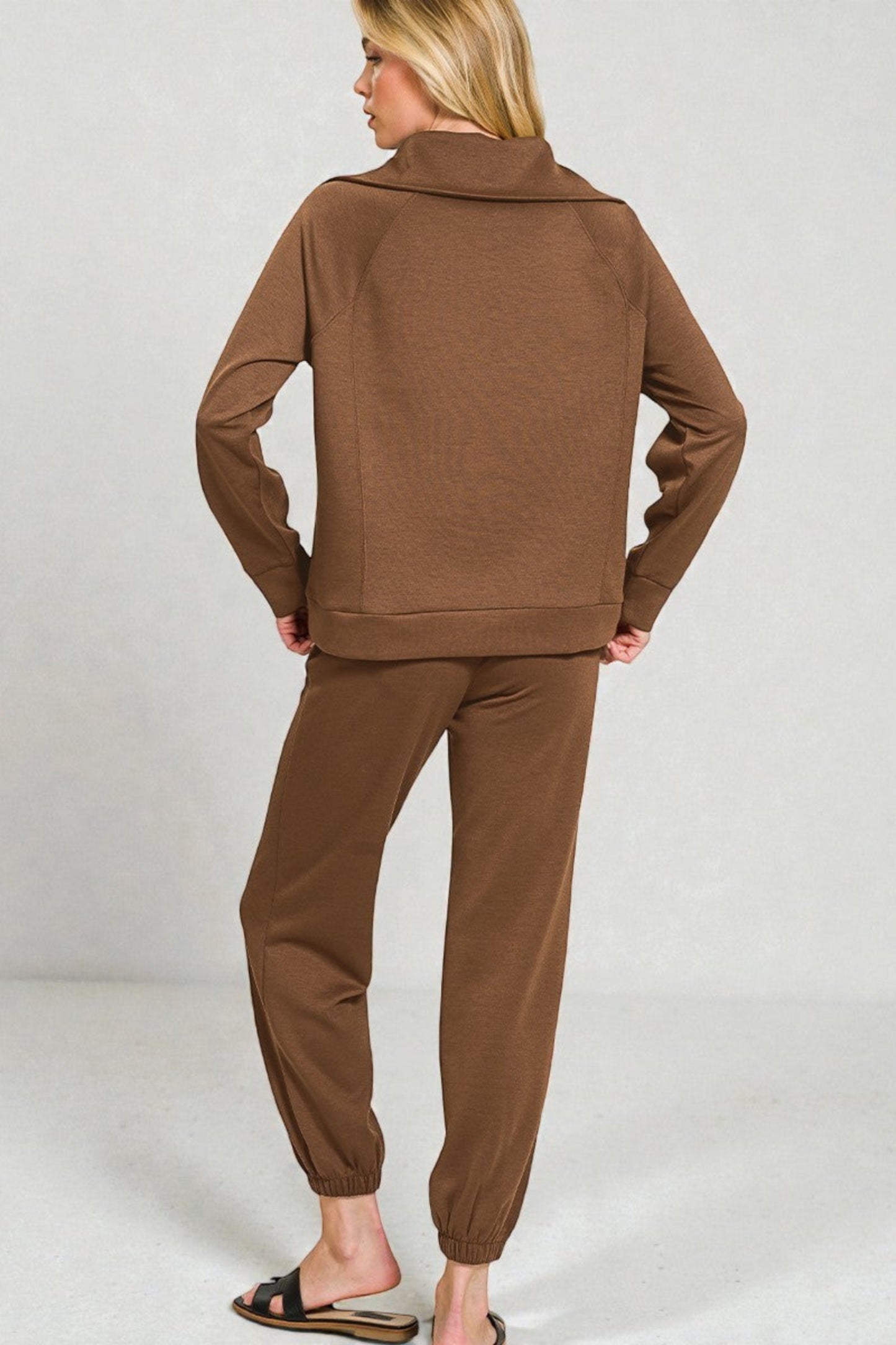 Woman wearing a brown tracksuit against a plain background