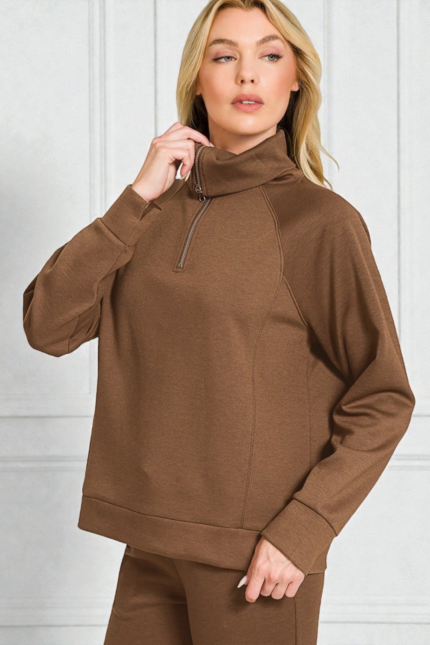 Woman wearing a brown high-neck sweater against a white background