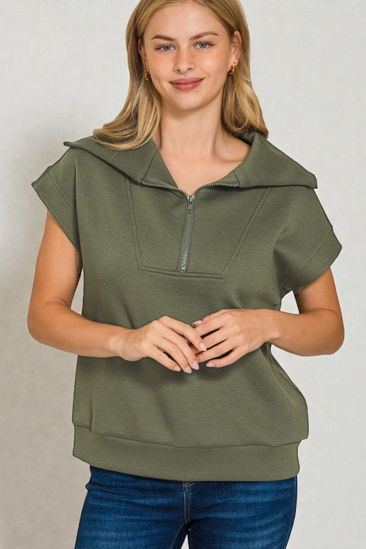 Woman wearing a green hooded top with a plain background