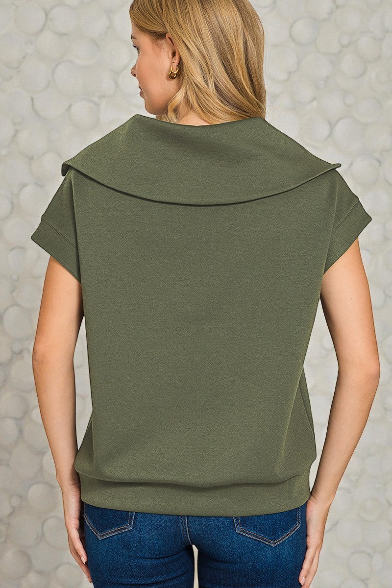 Person wearing an olive green top with a textured gray background