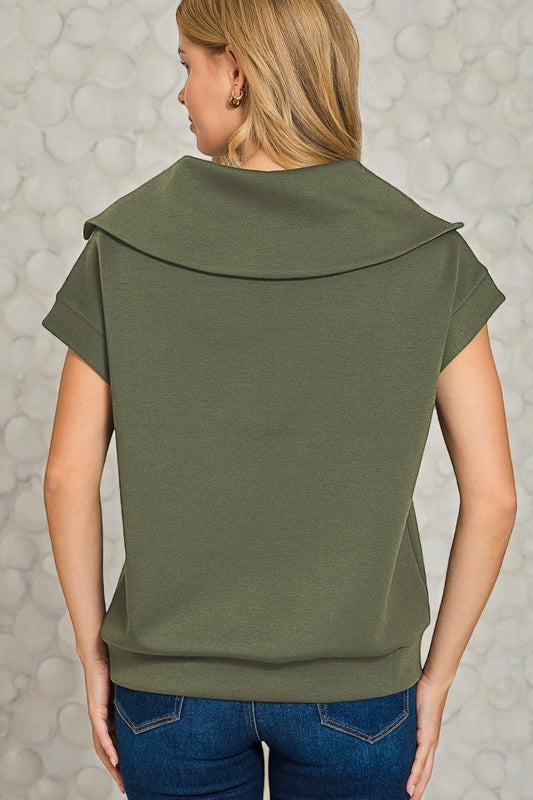 Person wearing an olive green top with a textured gray background