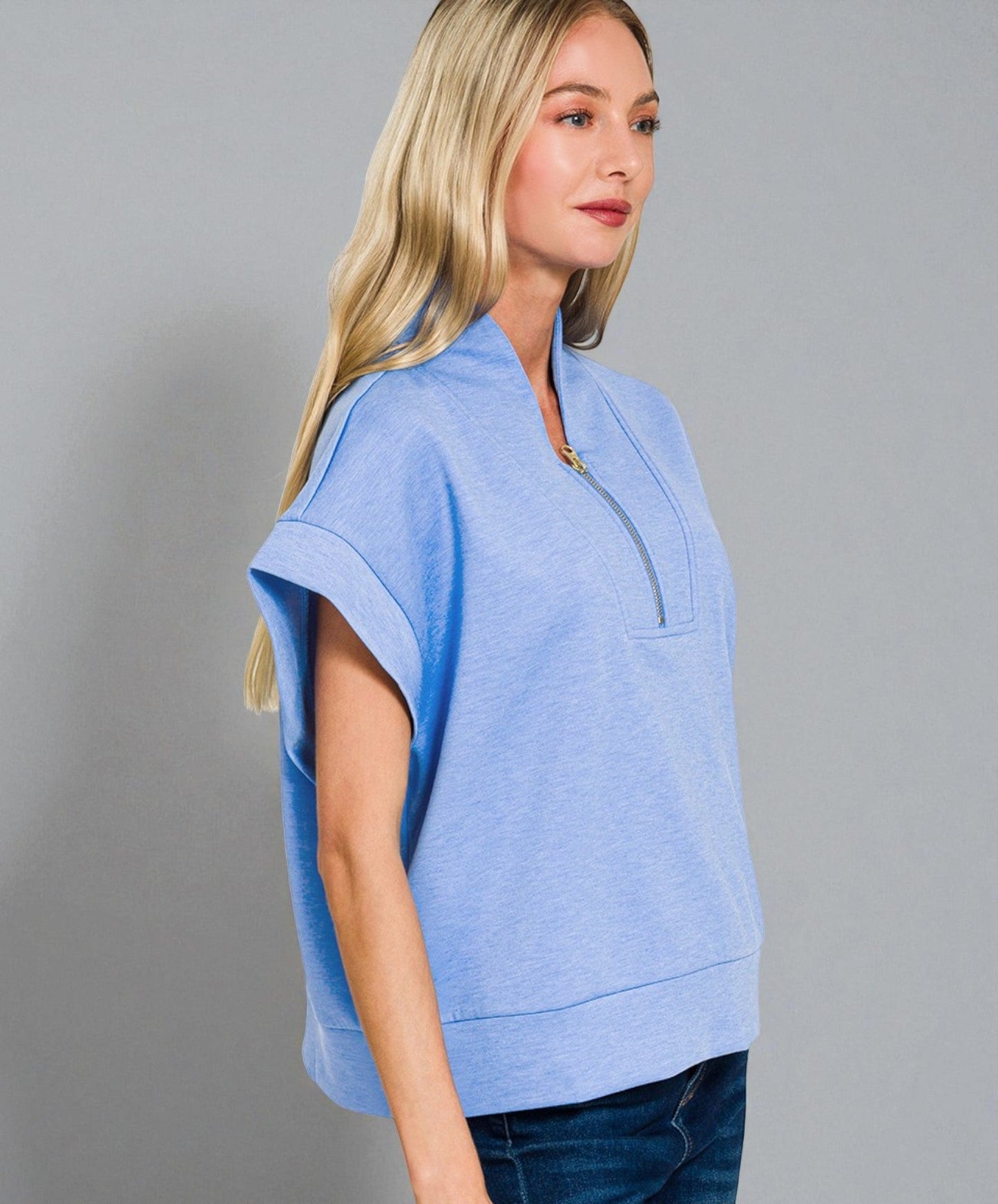 Woman wearing a light blue shirt with a collar against a gray background