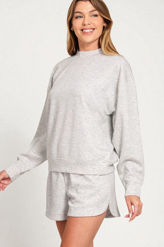 Woman wearing a gray sweatshirt and shorts set on a white background