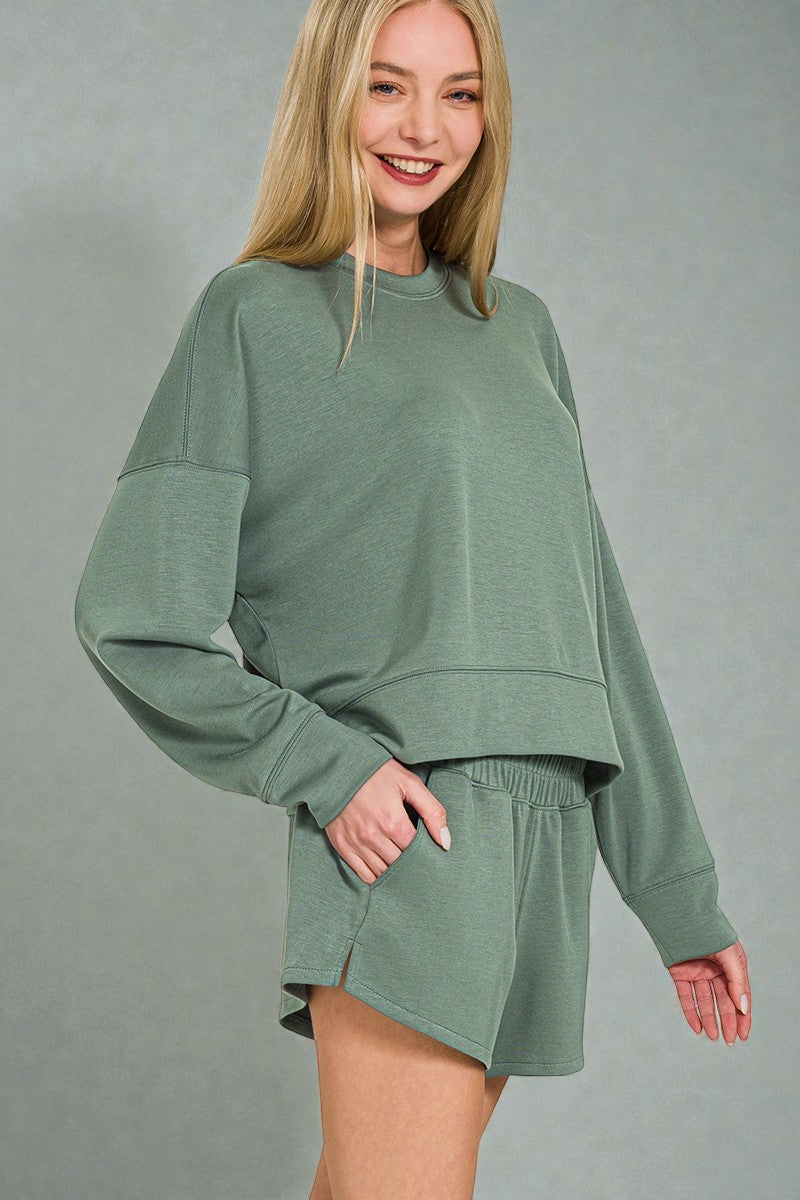 Woman wearing a green sweatshirt and shorts set on a gray background