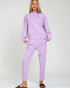 Woman wearing a matching lavender sweatshirt and pants set on a white background