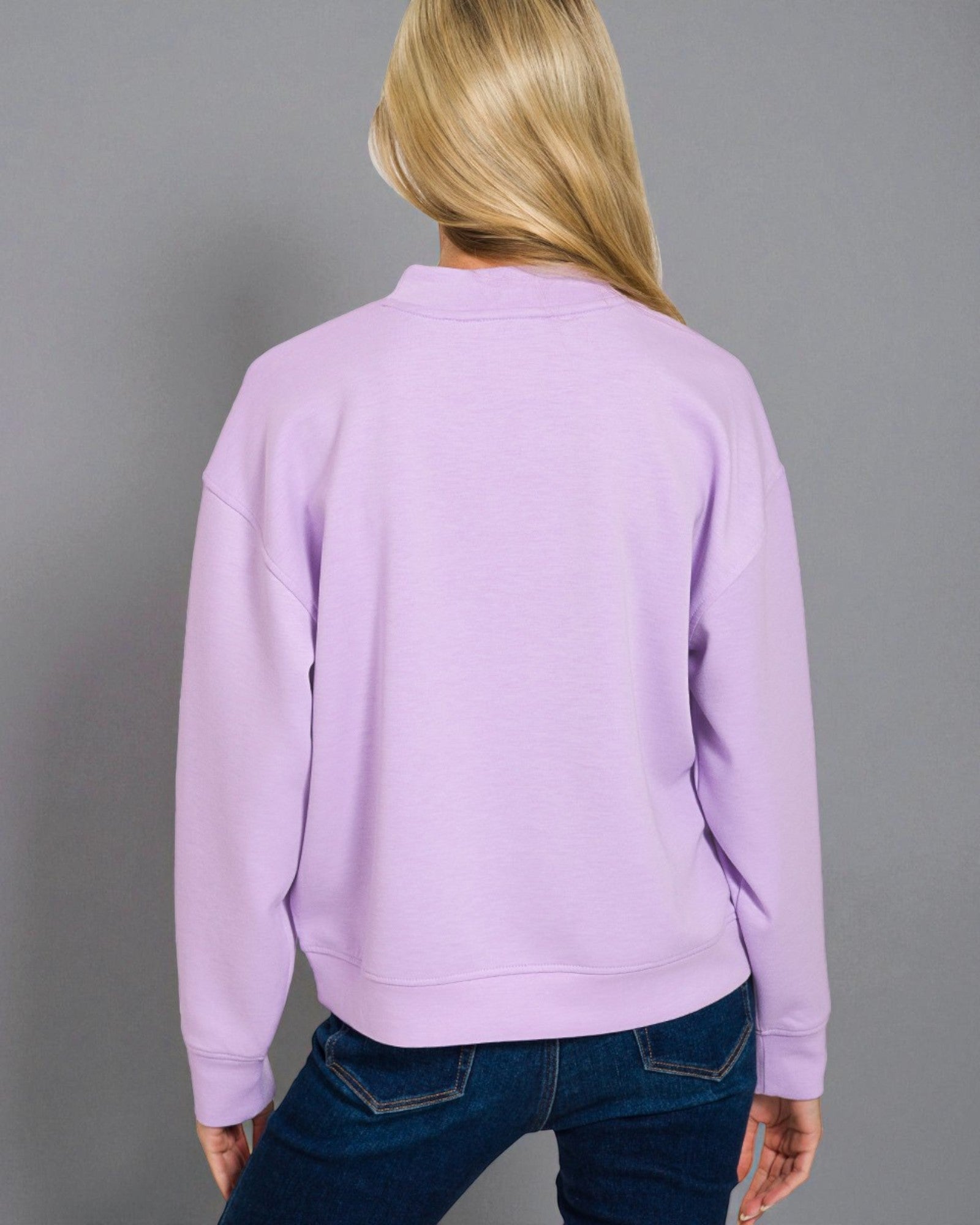 Person wearing a light purple sweatshirt against a gray background