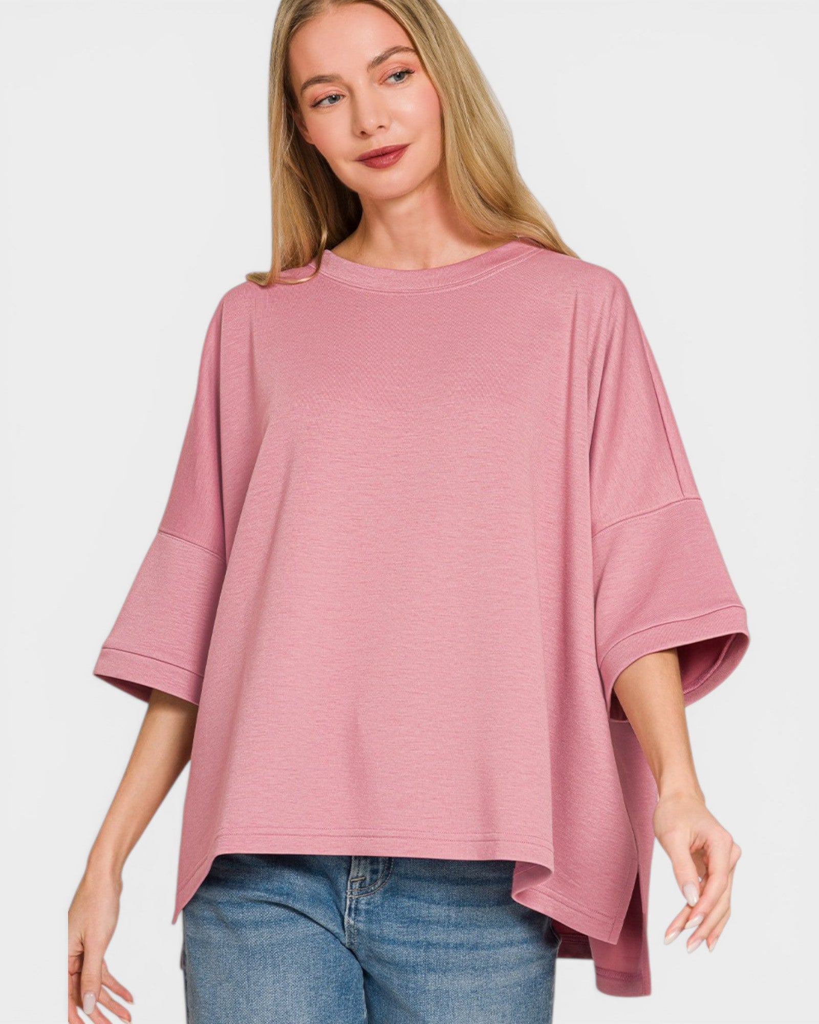 Woman wearing a pink oversized top and blue jeans on a white background