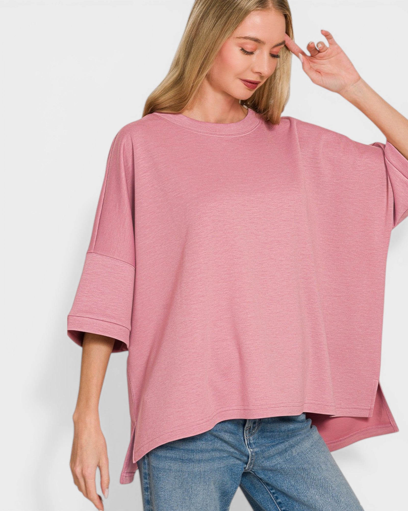 Woman wearing a pink oversized t-shirt and blue jeans on a white background
