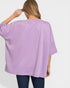 Person wearing a purple oversized shirt on a white background