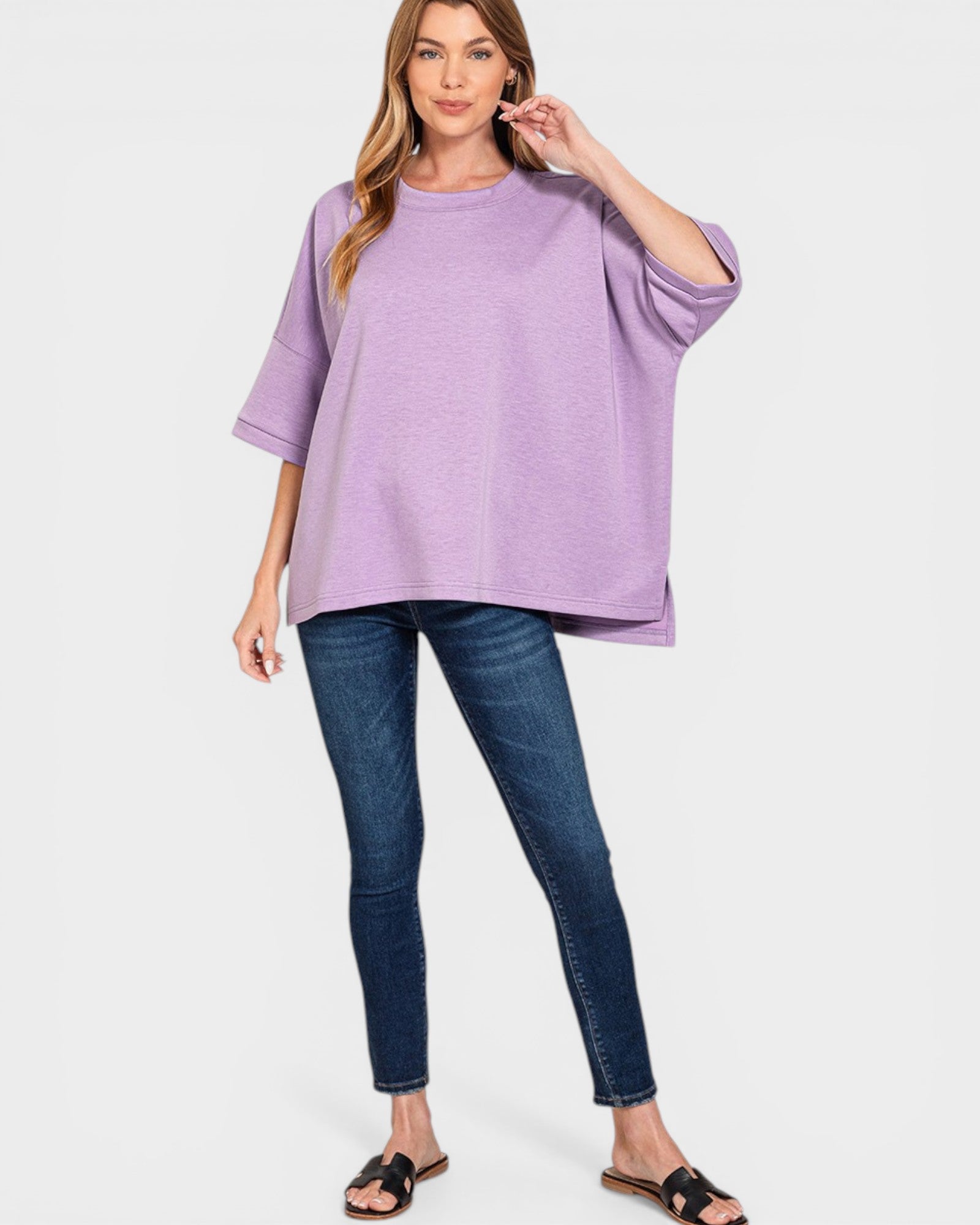 Woman wearing a purple top and blue jeans on a white background