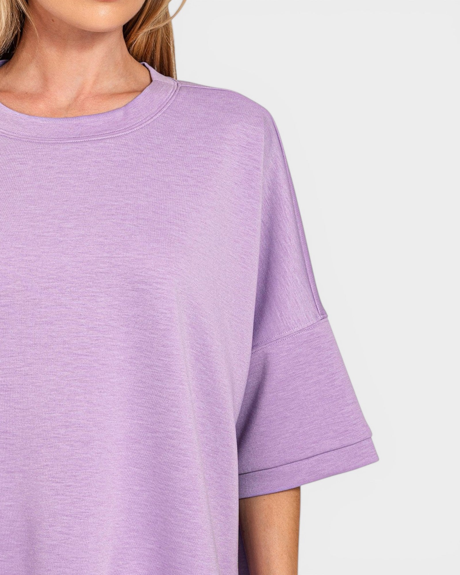 Close-up of a person wearing a light purple shirt with a plain background