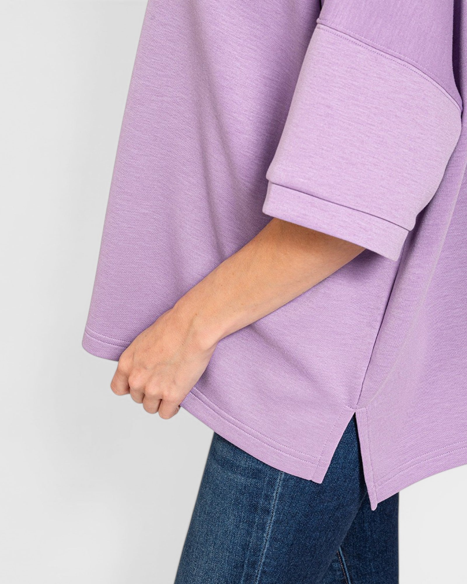 Purple sweater being worn with a plain background