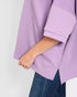 Purple sweater being worn with a plain background
