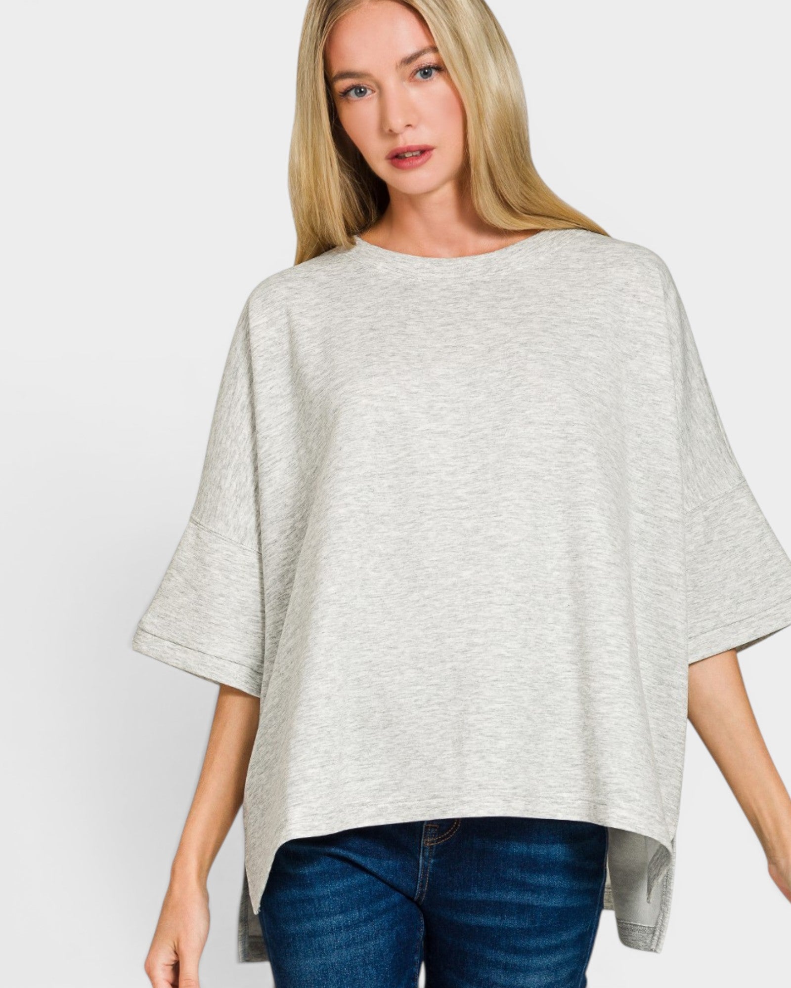 Woman wearing a gray poncho over a blue top on a white background