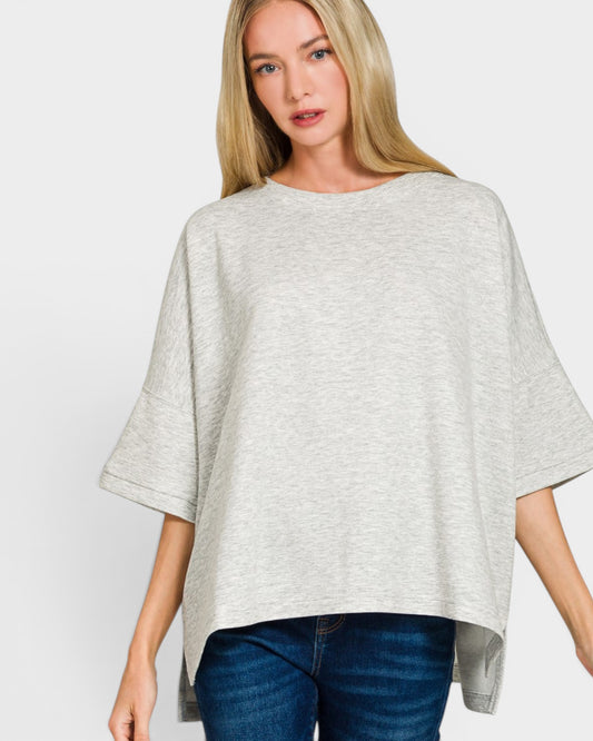 Woman wearing a gray poncho over a blue top on a white background
