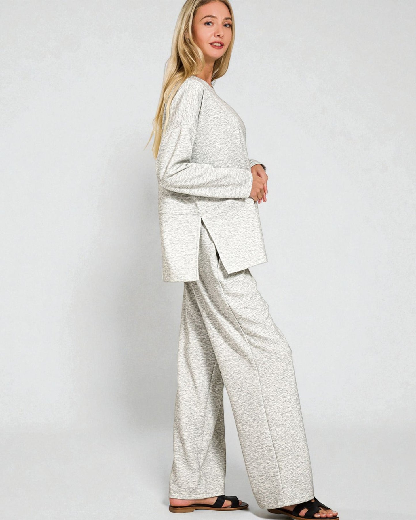 Woman wearing a light gray suit with wide-leg pants on a white background