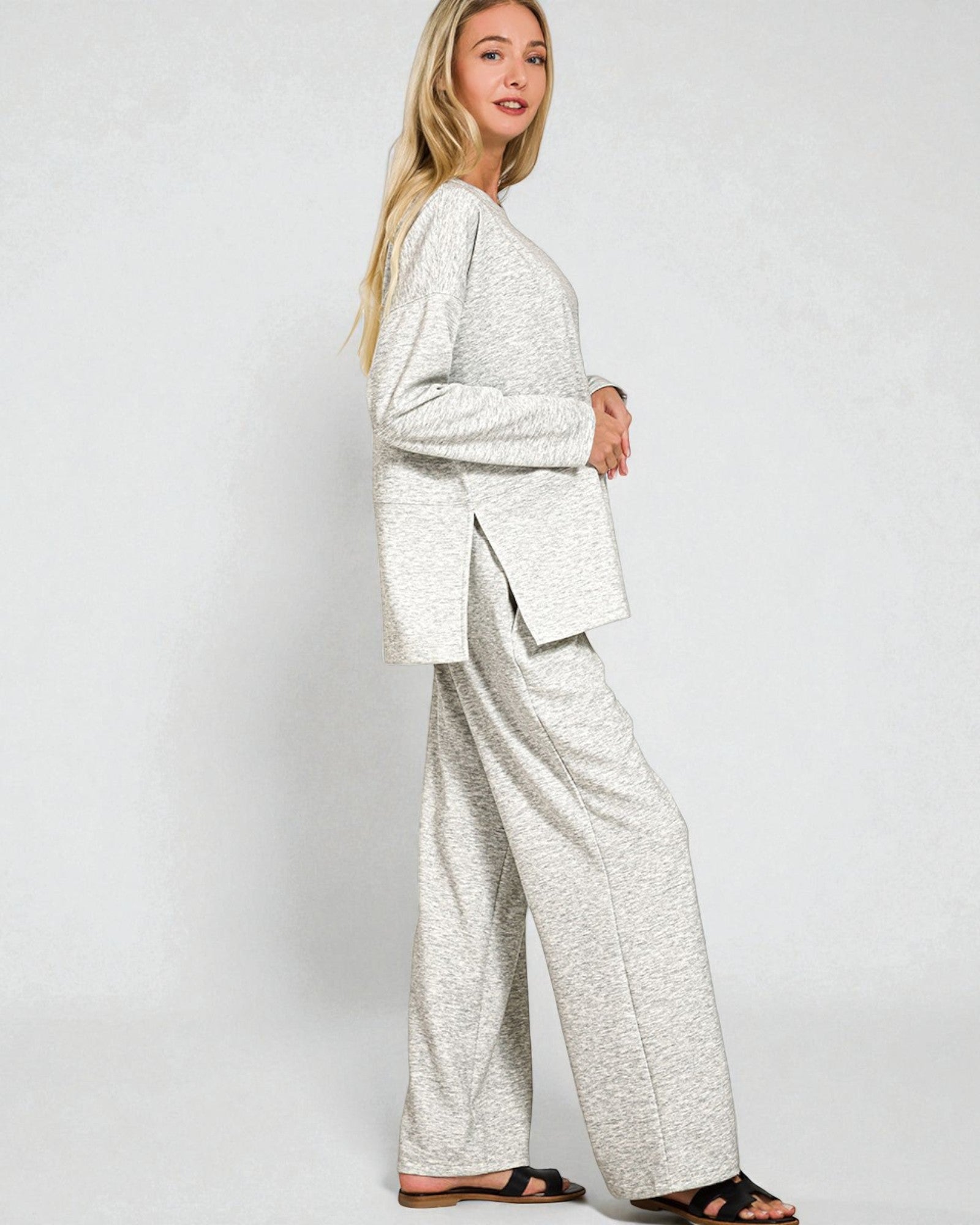 Woman wearing a light gray suit with wide-leg pants on a white background