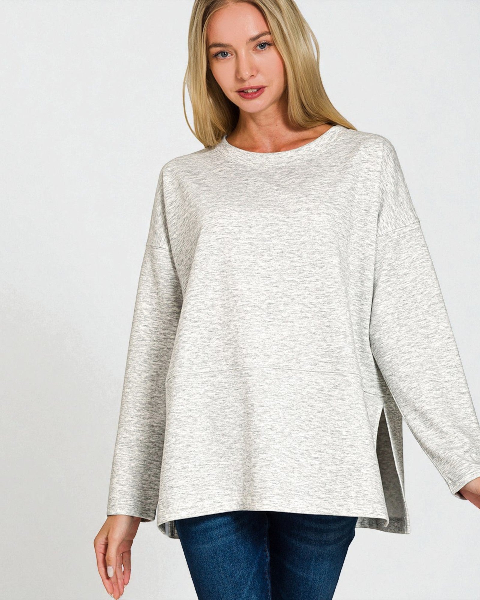 Woman wearing a light gray sweater with a plain background