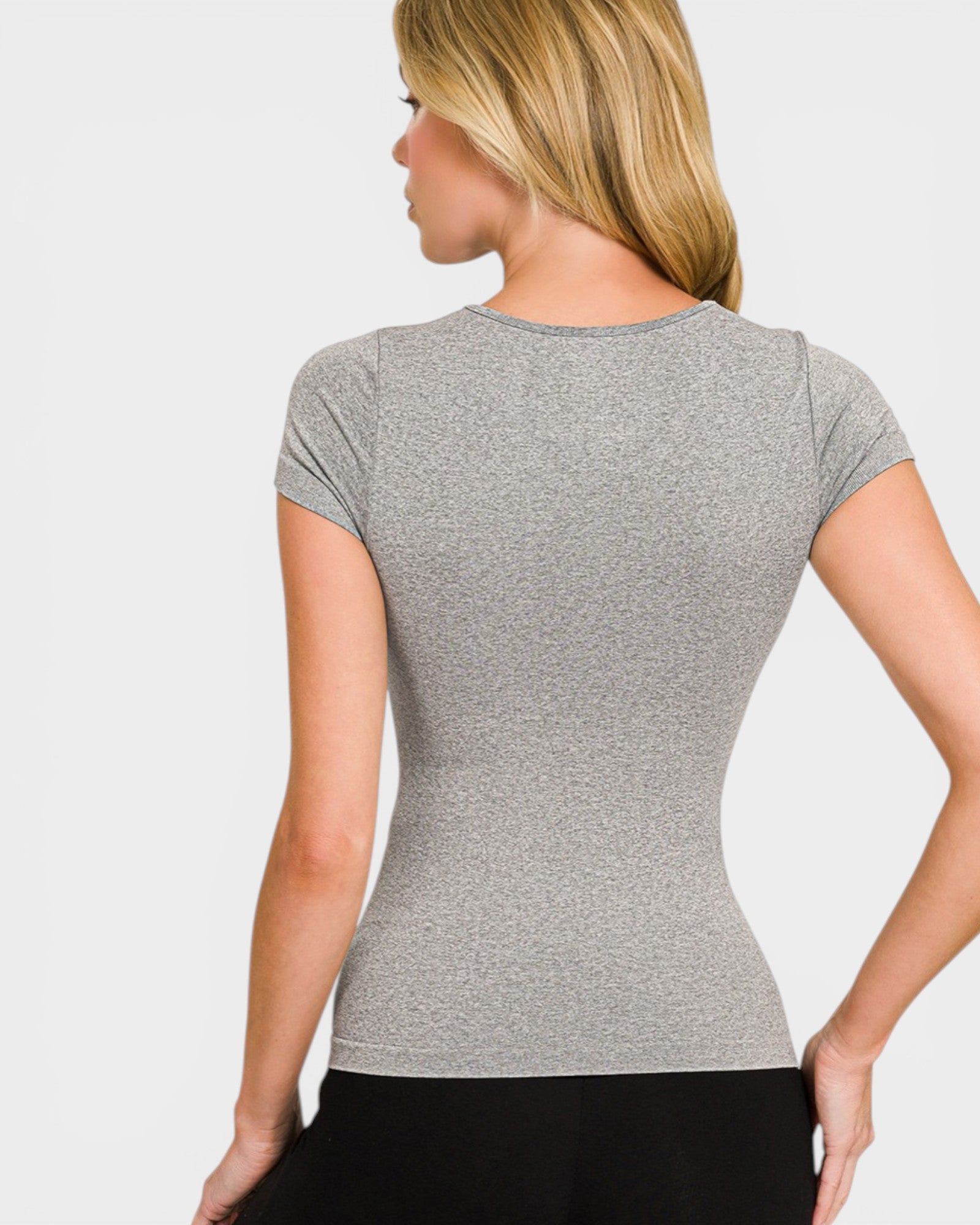 Woman wearing a gray short-sleeve top against a plain background