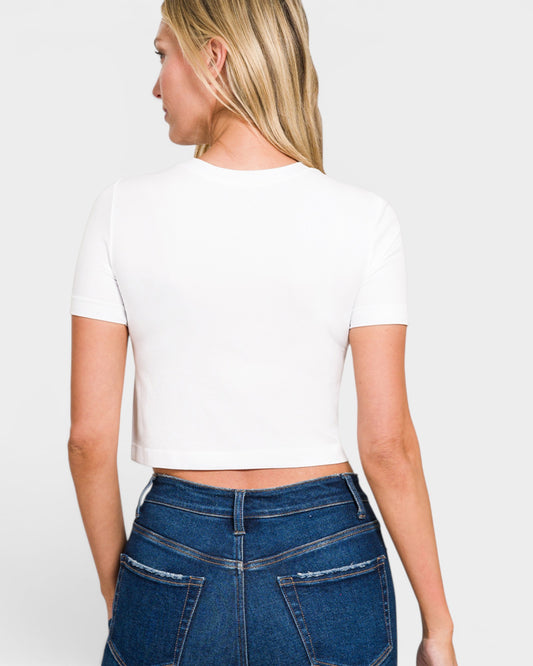 Person wearing a white crop top and blue jeans on a plain background