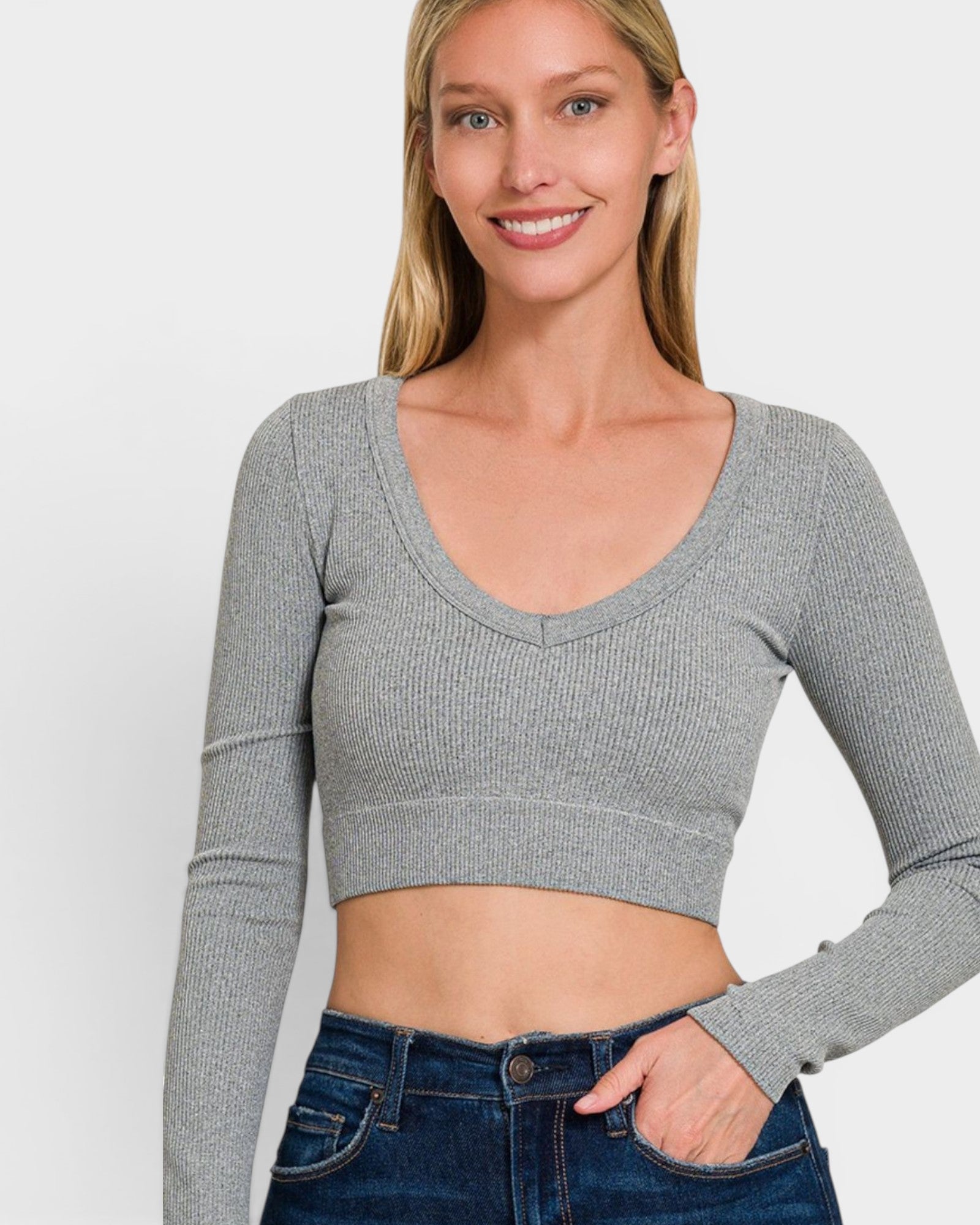 Woman wearing a gray long-sleeve crop top against a white background