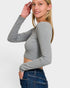 Woman wearing a gray long-sleeve crop top and blue jeans on a white background