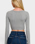 Person wearing a gray long-sleeve crop top and blue jeans on a white background