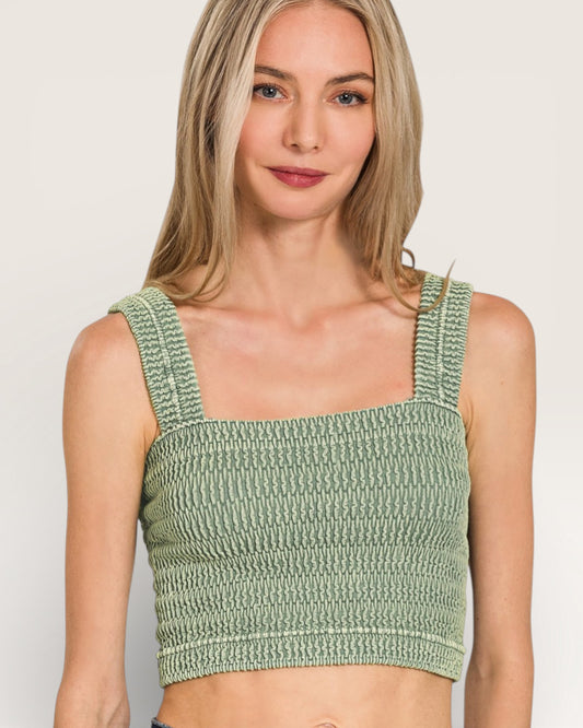 Woman wearing a green crochet top against a plain background