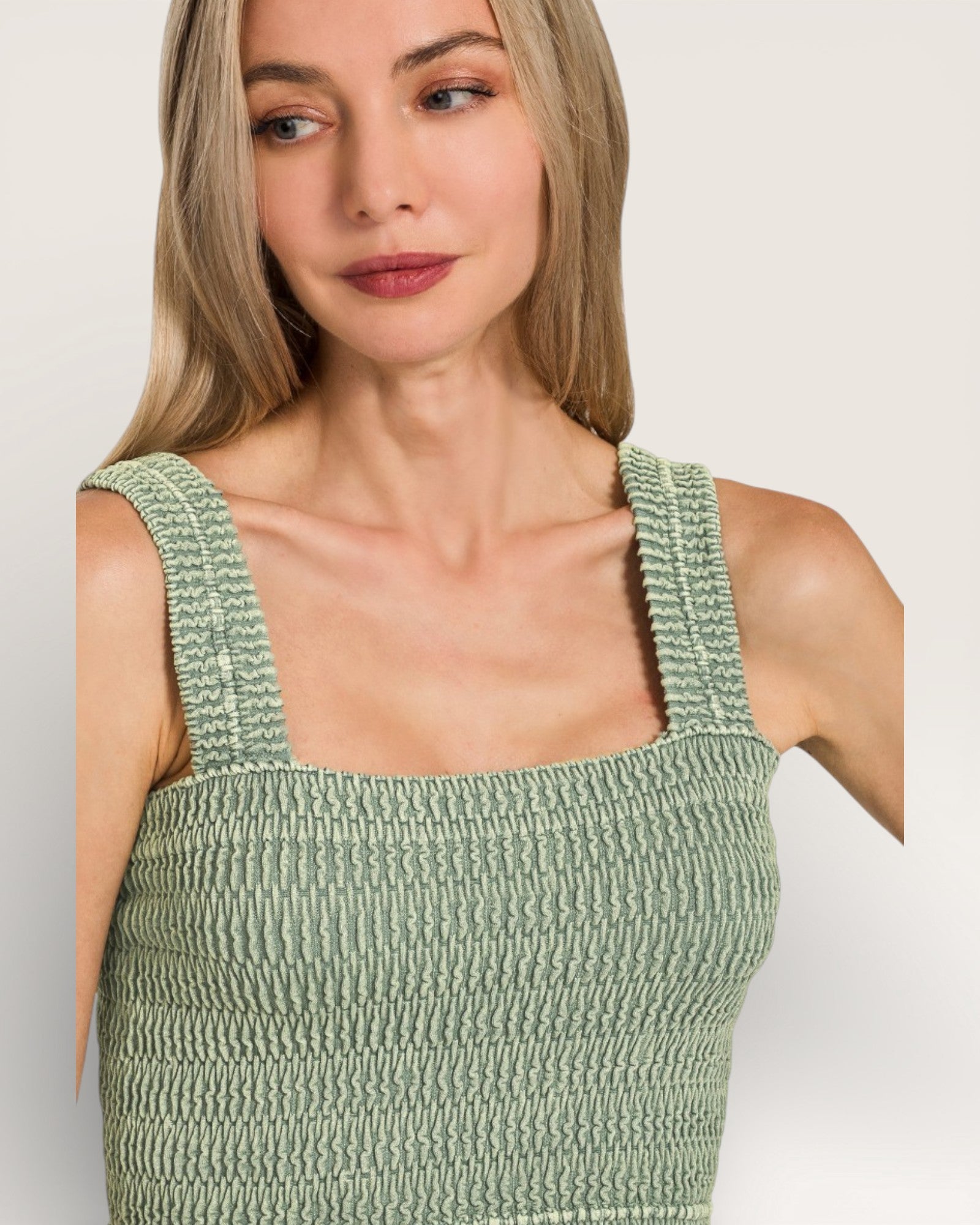 Woman wearing a green smocked dress against a plain background