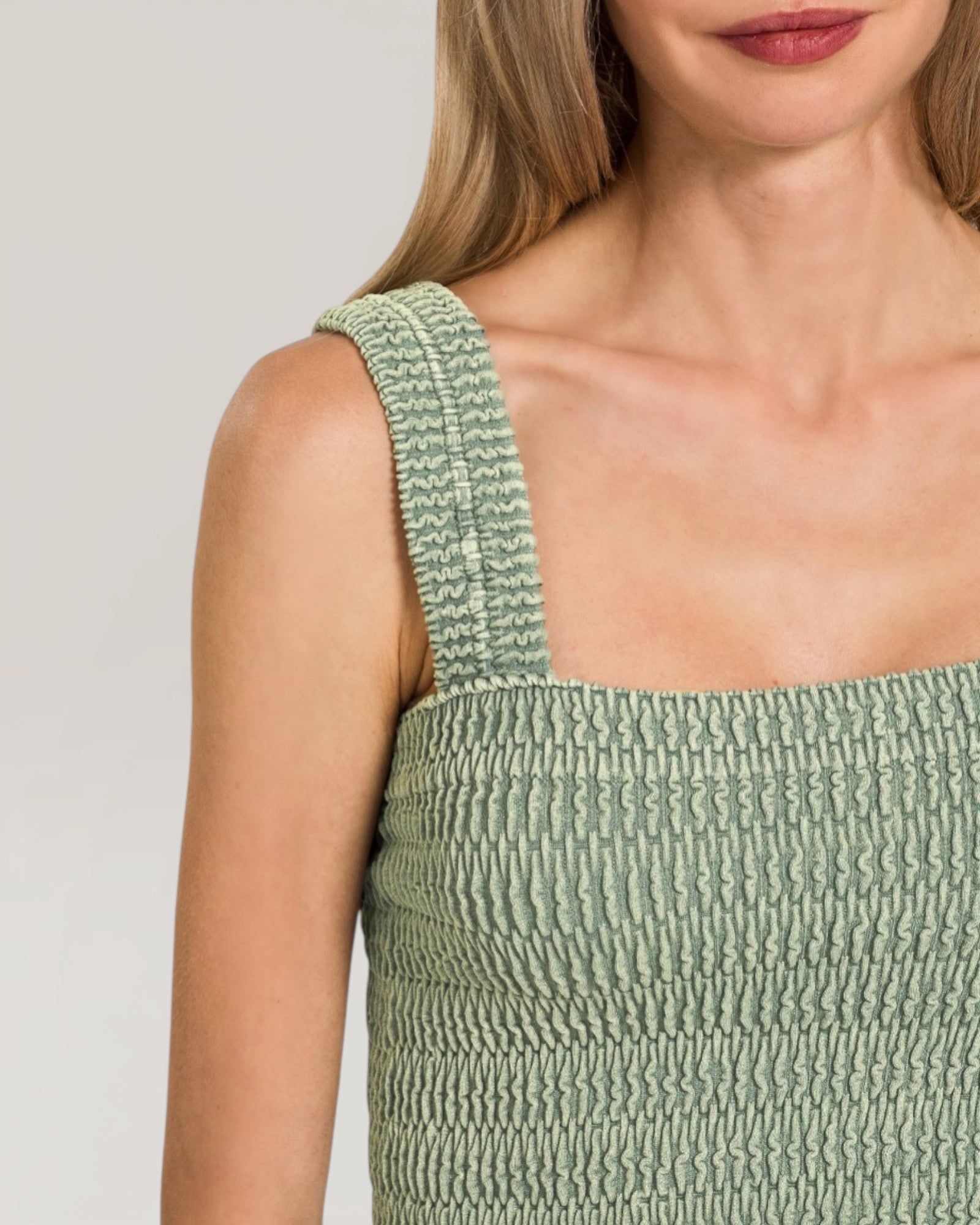 Green textured dress with straps on a plain background