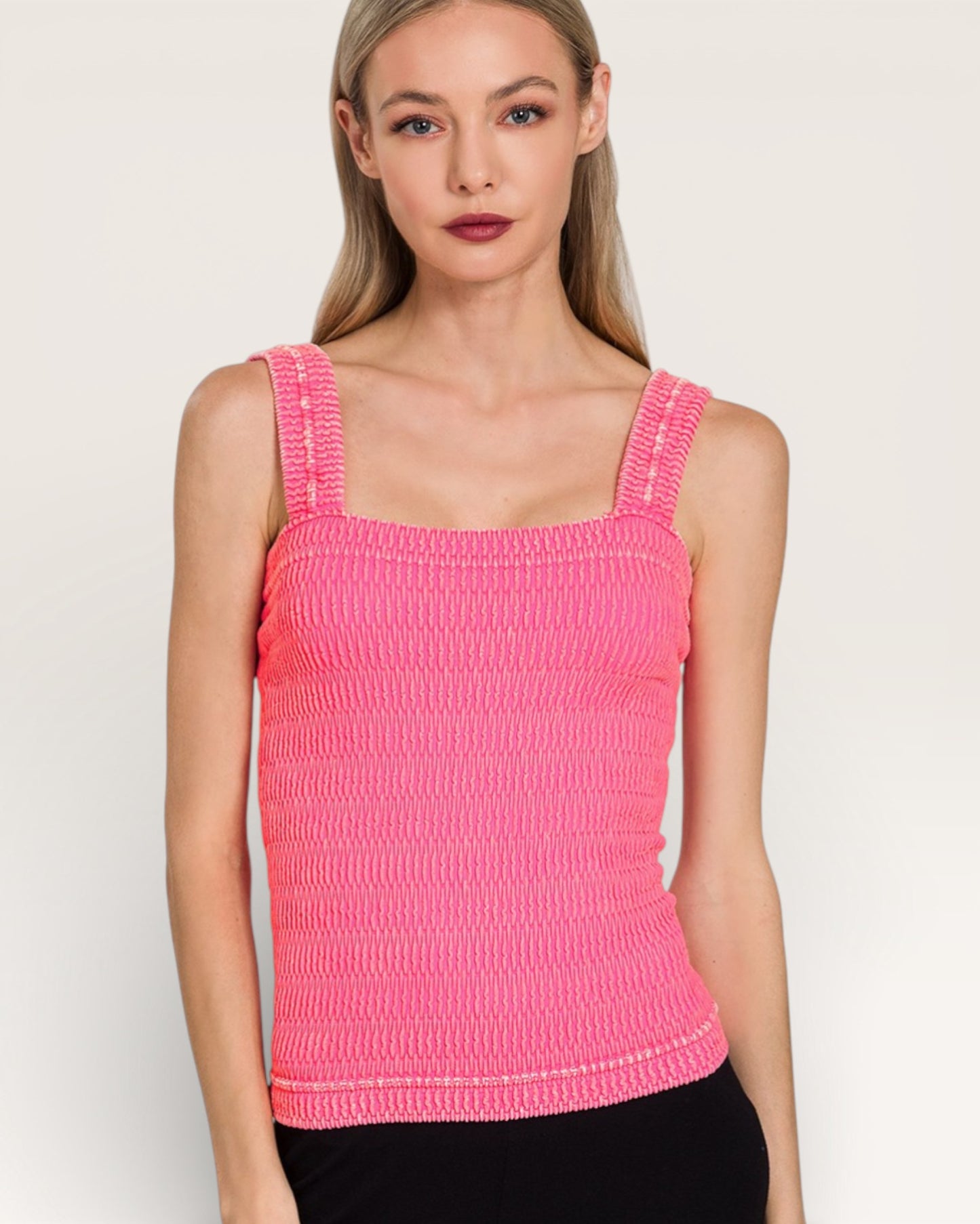 Woman wearing a pink textured tank top against a plain background