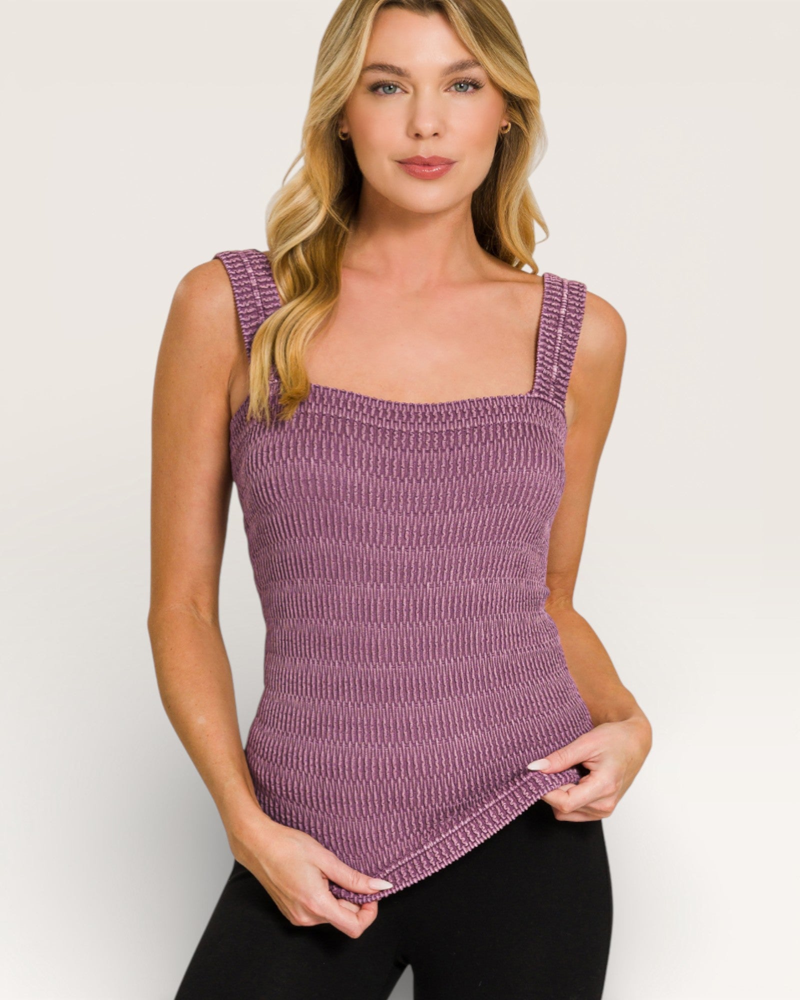 Woman wearing a purple knitted tank top against a plain background