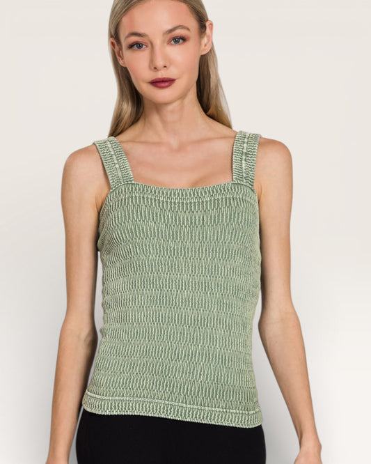 Woman wearing a green knitted tank top against a plain background