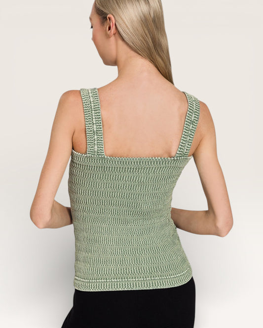 Woman wearing a green knitted tank top against a plain background