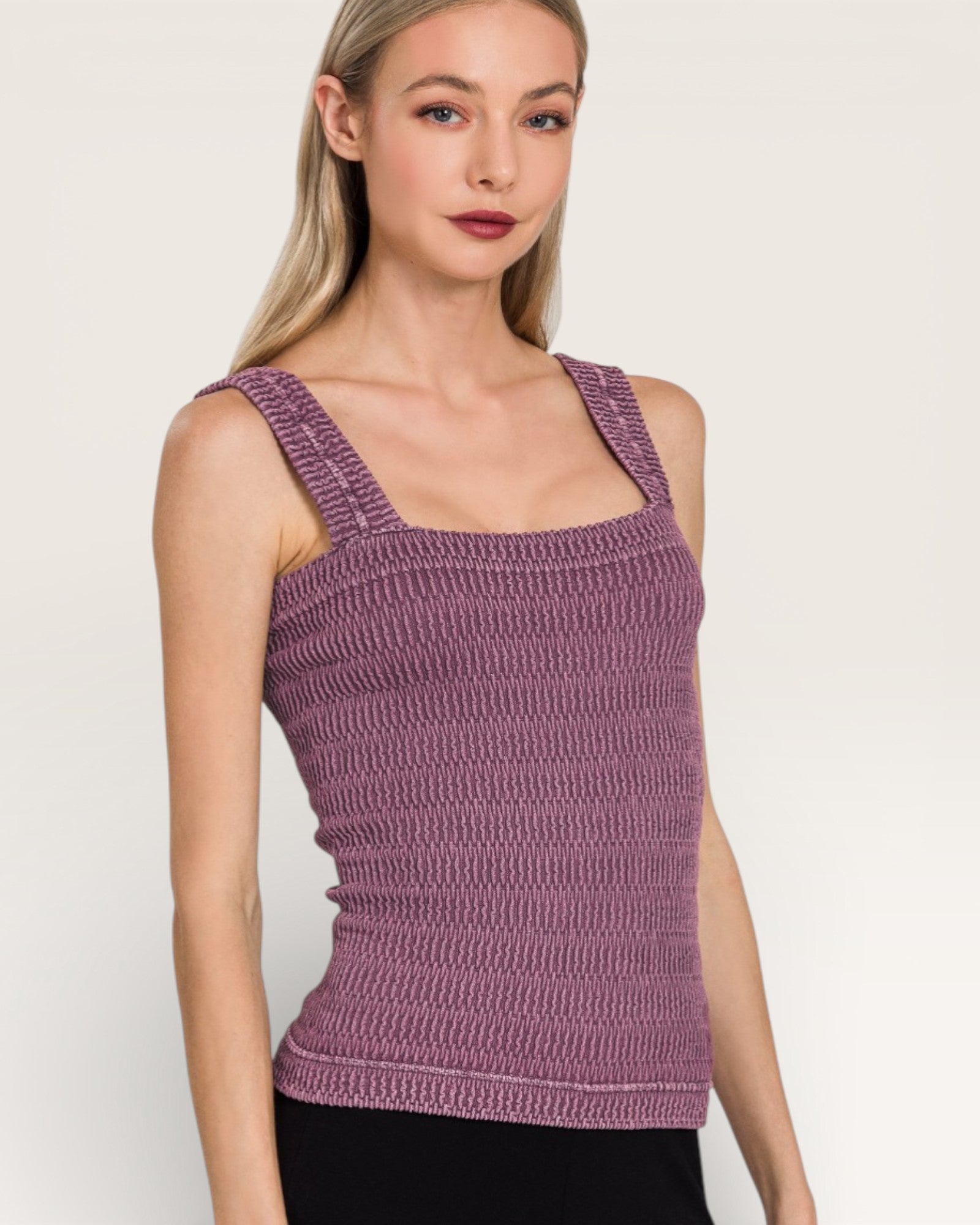 Woman wearing a purple knitted tank top against a plain background