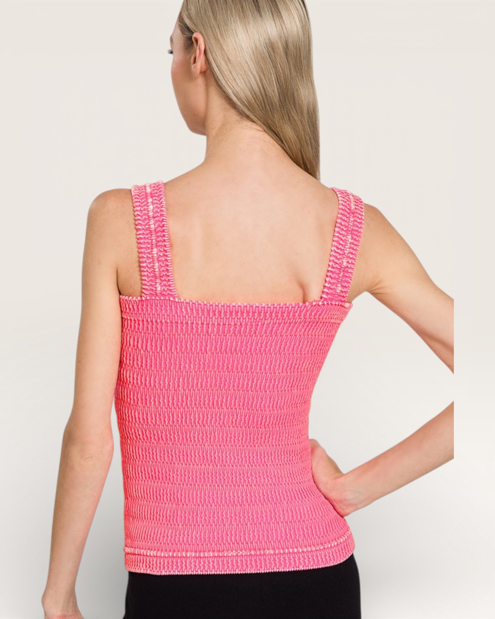 Woman wearing a pink crochet tank top against a plain background