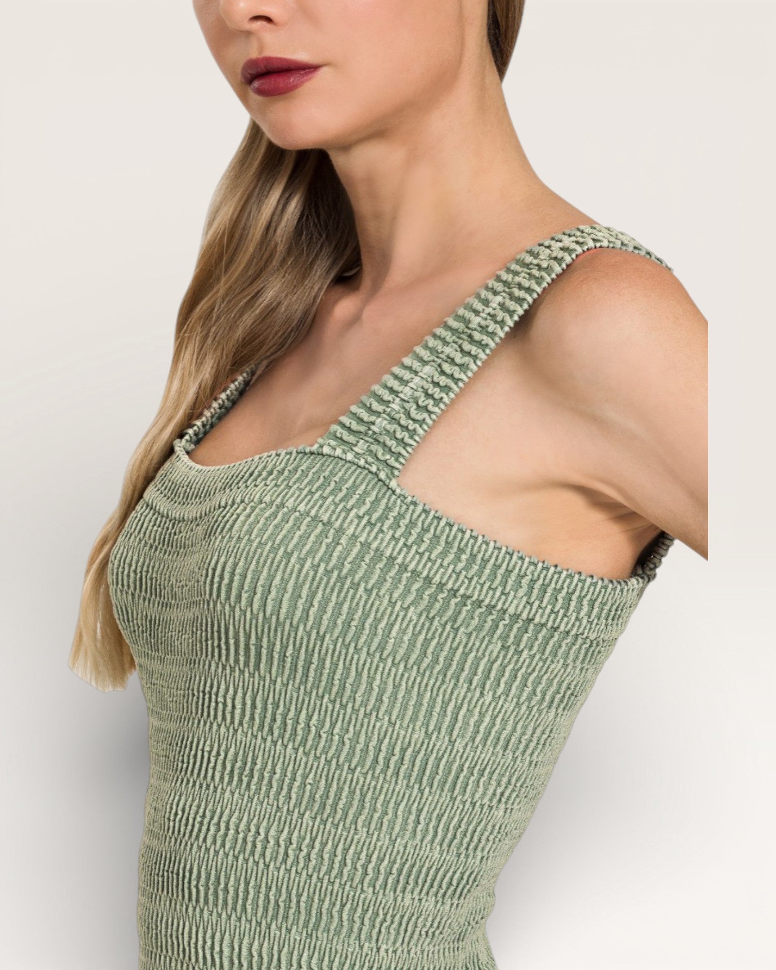 Woman wearing a green ribbed tank top against a plain background