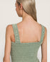 Woman wearing a green knitted sleeveless top against a plain background