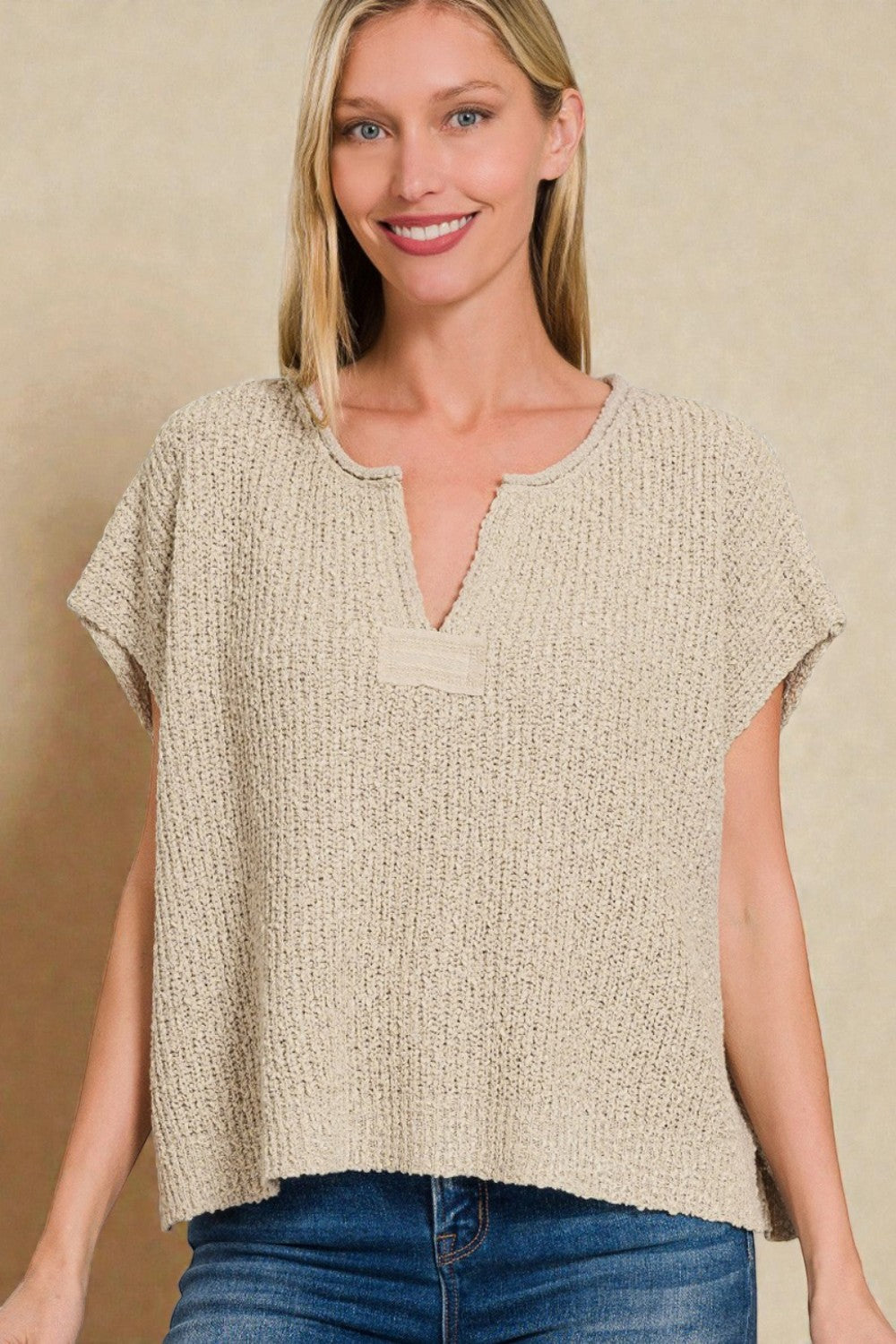 Woman wearing a beige textured top against a beige background