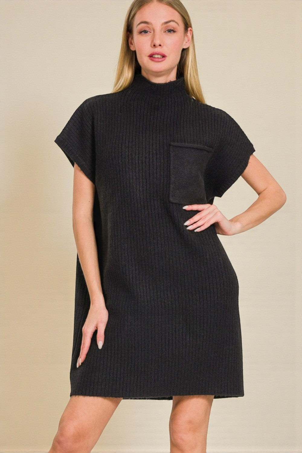 Woman wearing a black ribbed knit dress against a beige background