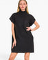A woman modeling a black ribbed knit mock-neck mini dress with short sleeves and a chest pocket, set against a plain white studio background.