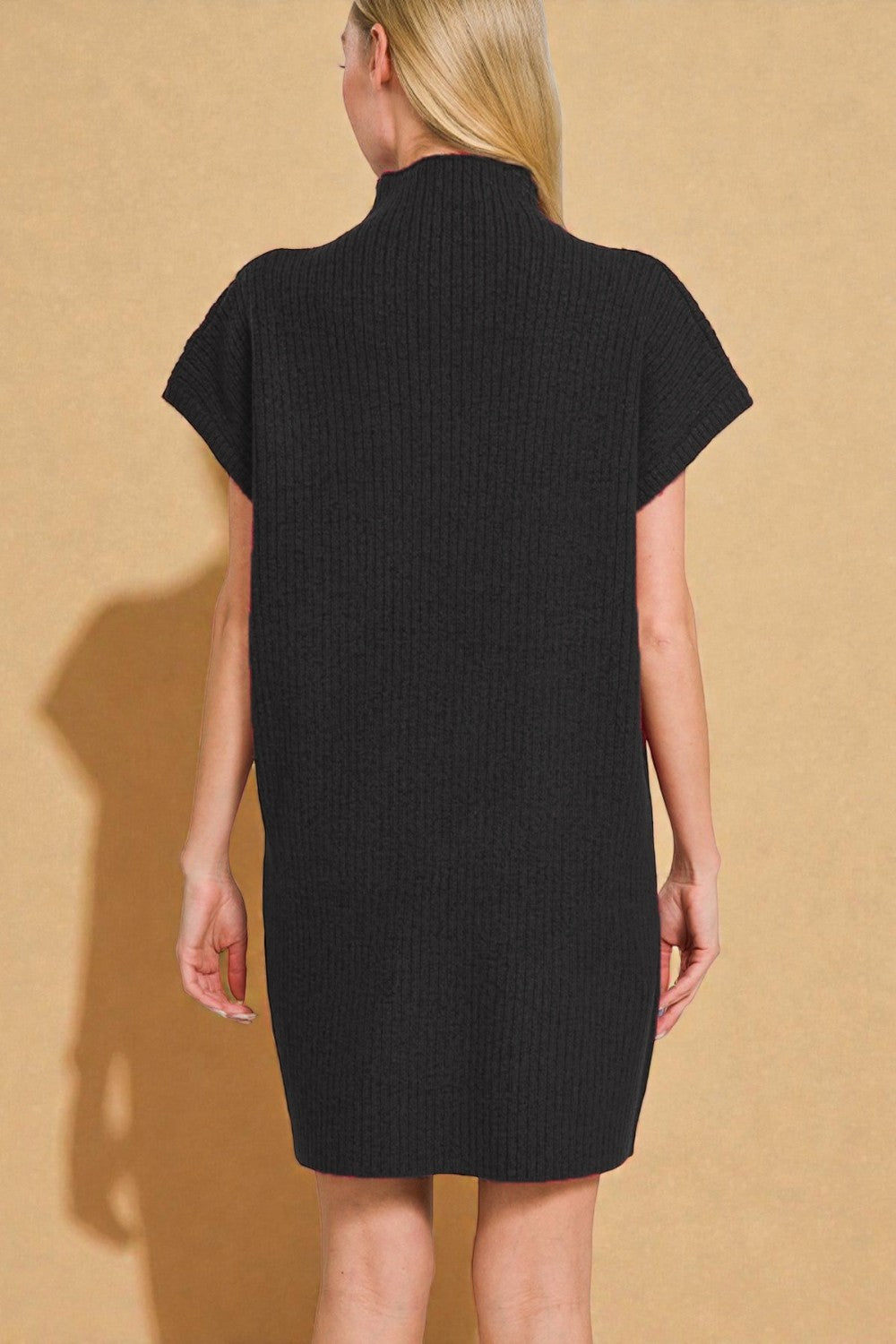 Person wearing a black dress against a beige background