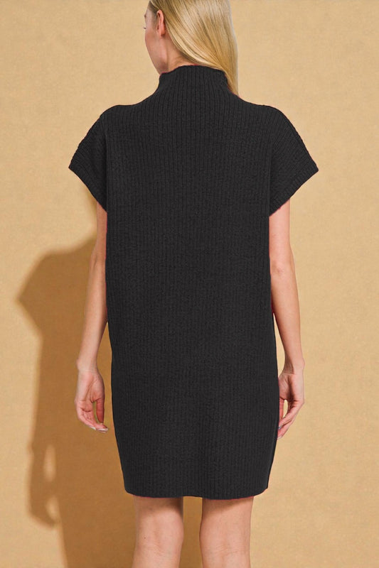 Person wearing a black dress against a beige background