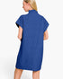A woman shown from the back wearing a blue ribbed knit mock-neck dress with short sleeves, photographed against a clean white studio background.