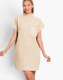 A woman modeling a beige ribbed knit mock-neck mini dress with short sleeves and a chest pocket, set against a plain light gray studio background.