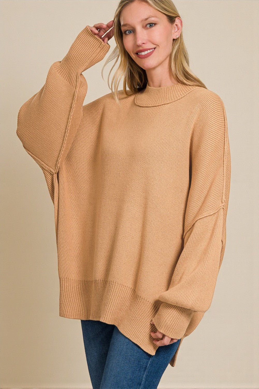 Woman wearing a beige sweater with a plain background